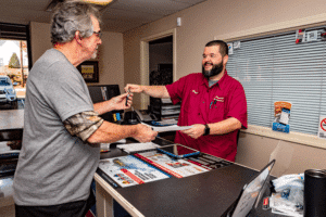 Why Choose a Local Auto Repair Shop in Greer, SC? with Eastside Automotive. Image of service advisor at the shop exchanging payment for car keys. to a customer after he received auto repair services.